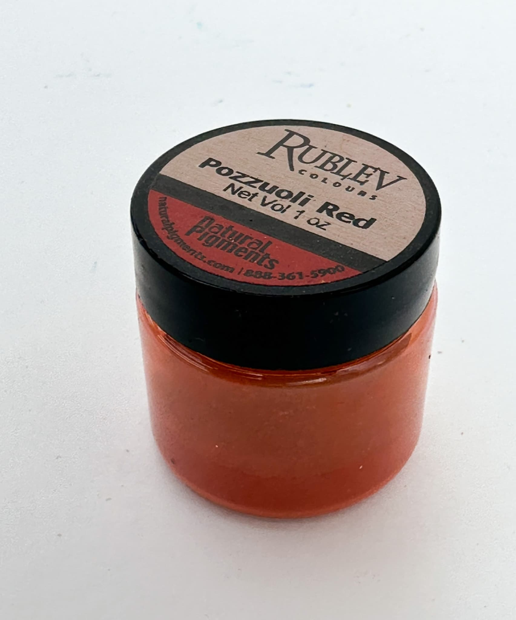 A jar of red-orange dry pigment