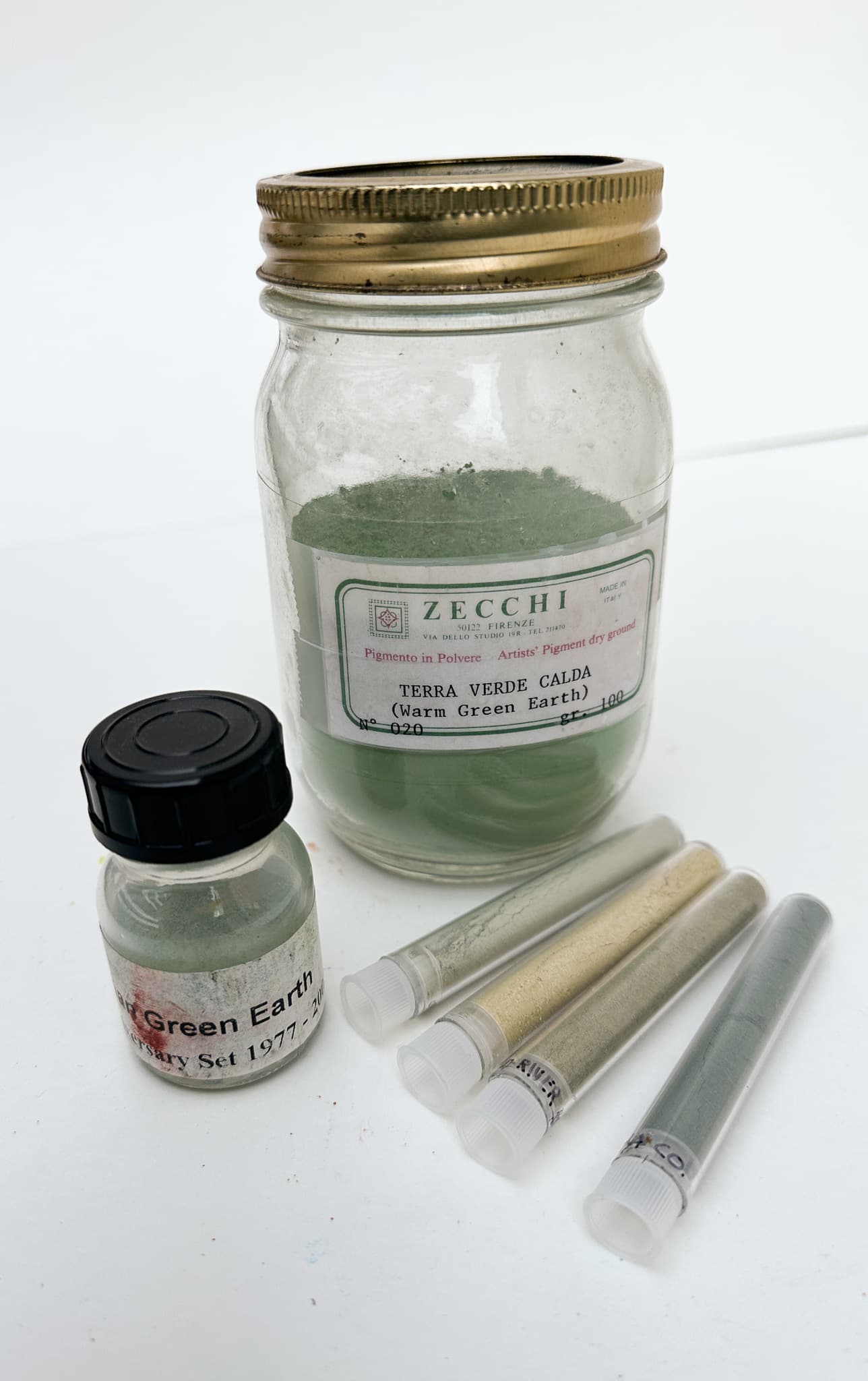 Multiple samples of green earth pigment ranging from dull green to straw colored