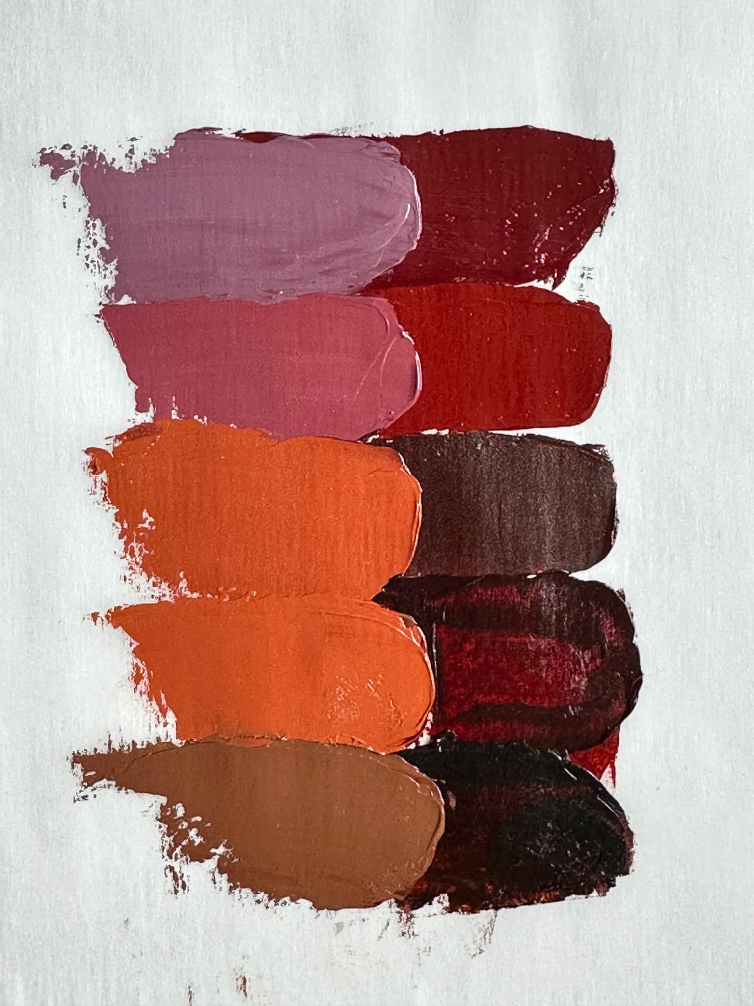 Five swatches of oil paint made with PR102 ranging from chocolate brown, to orange-brown, to dull red, to nearly red-violet