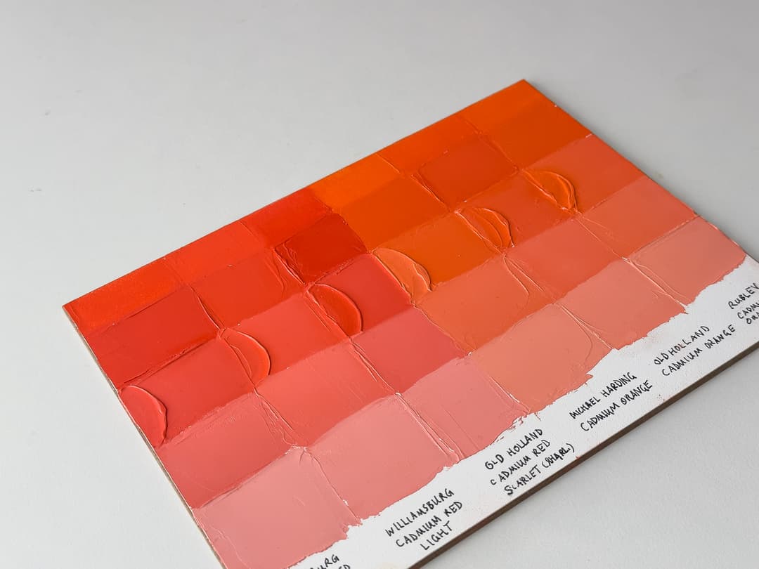 A variety of Cadmium Red Lights and Cadmium Orange in oil paints. Handpainted swatches made with a palette knife show the differences between paint brands