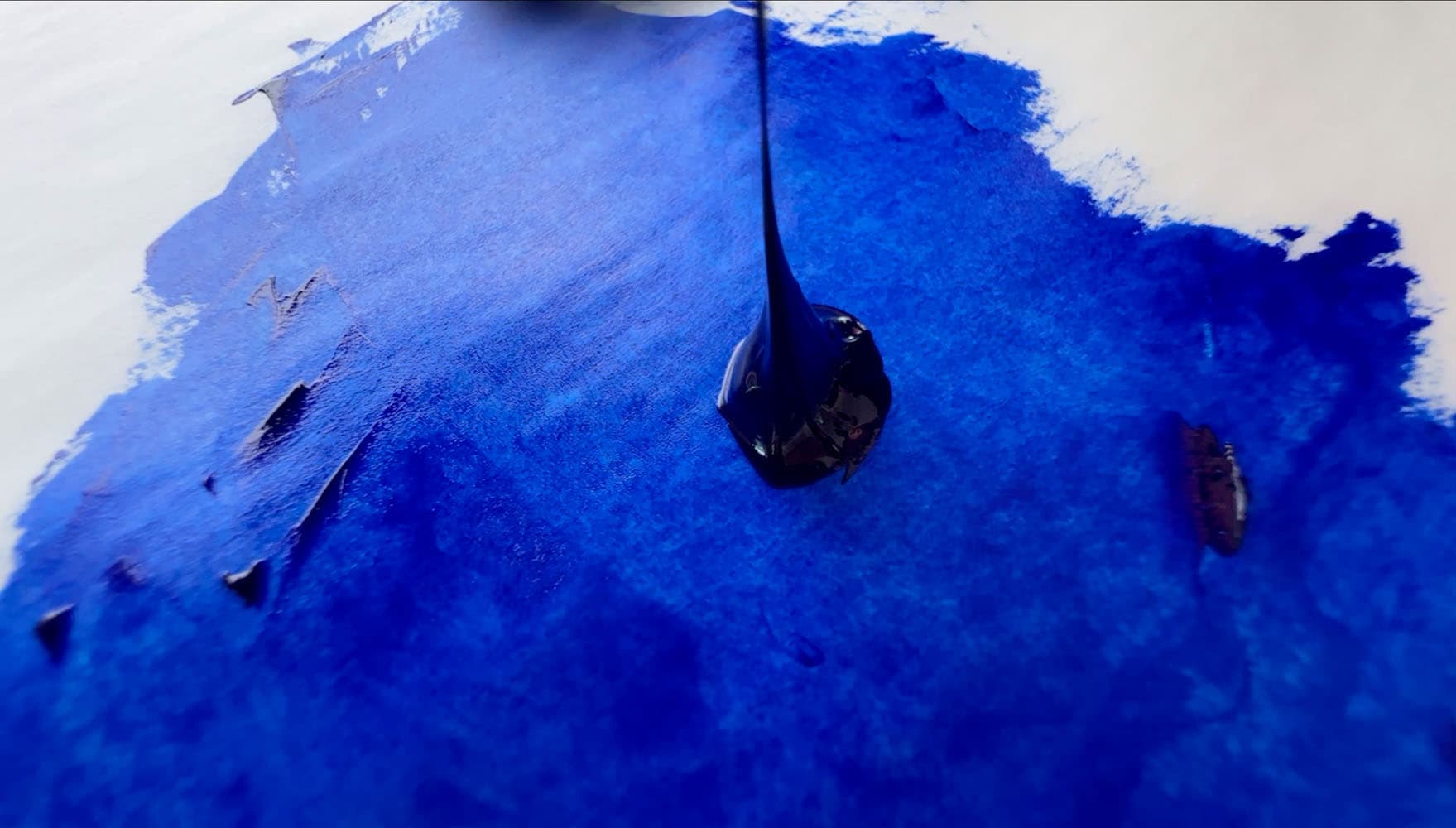 A dollop of ultramarine where the long paint is shown as a string connecting the dollop to the palette knife