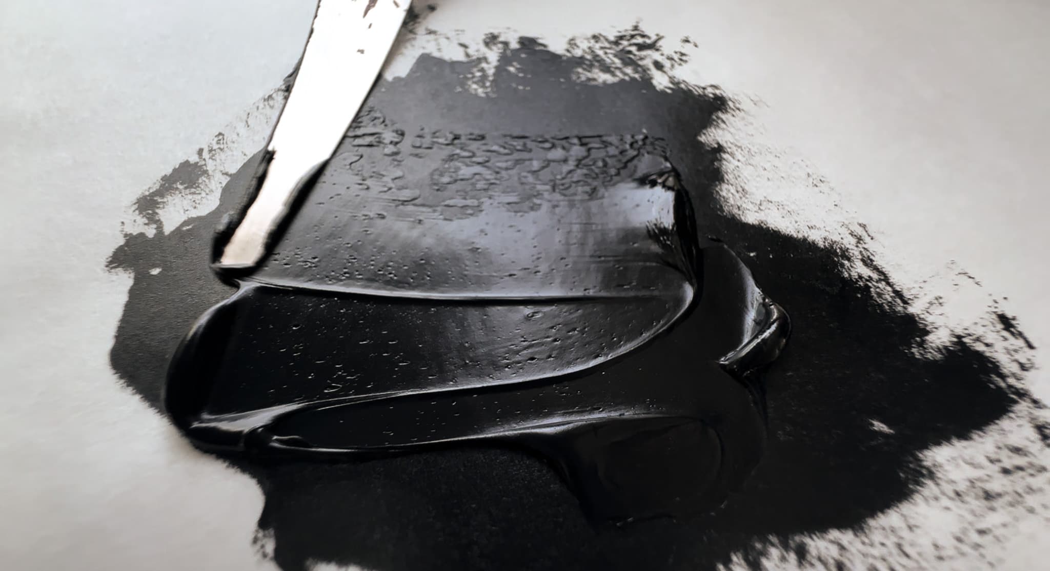 A stroke of Holbein Peach Black oil paint with a palette knife