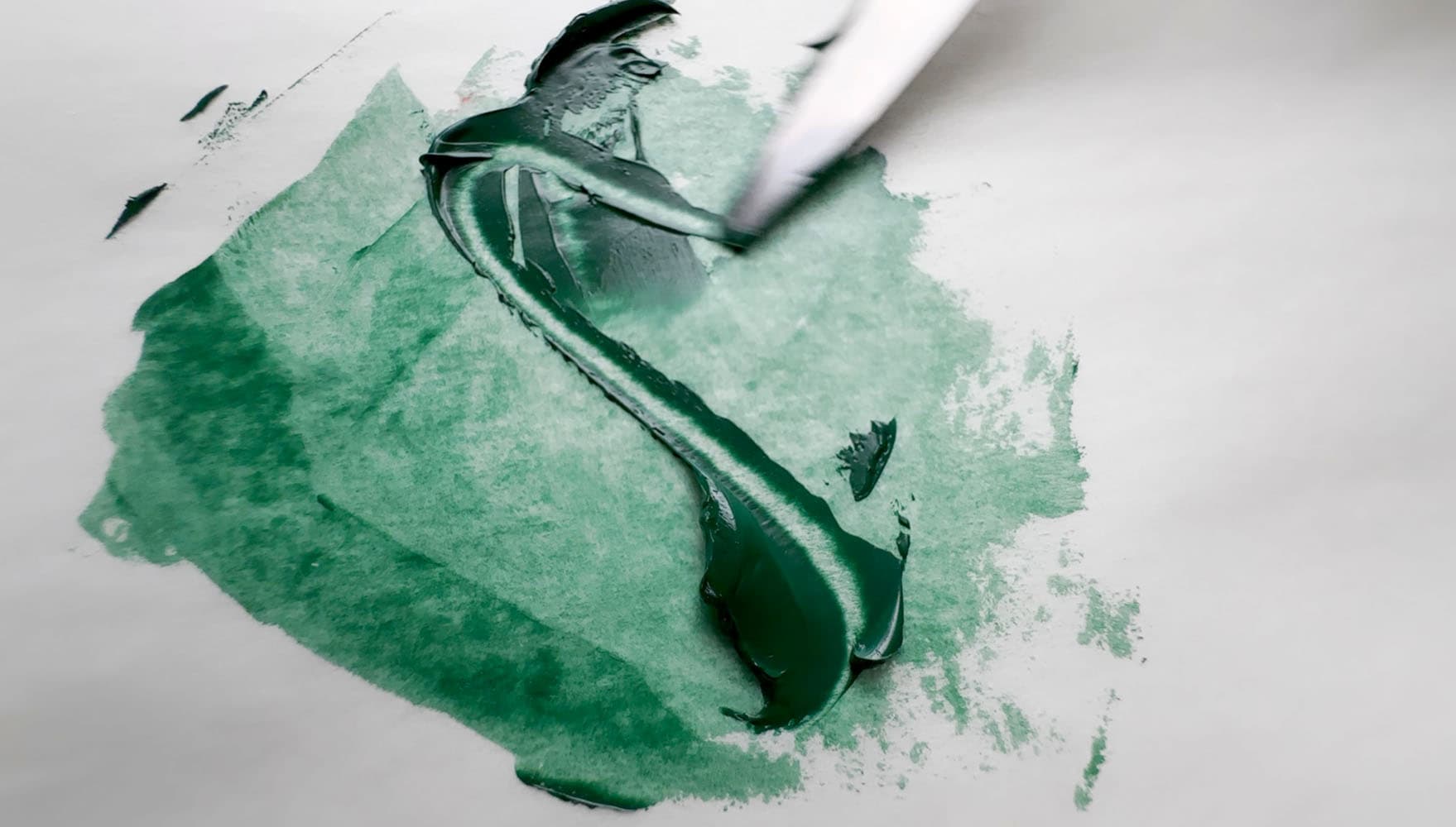 A swoosh of green oil paint made with PG19 that shows its semi-transparency when spread thinly