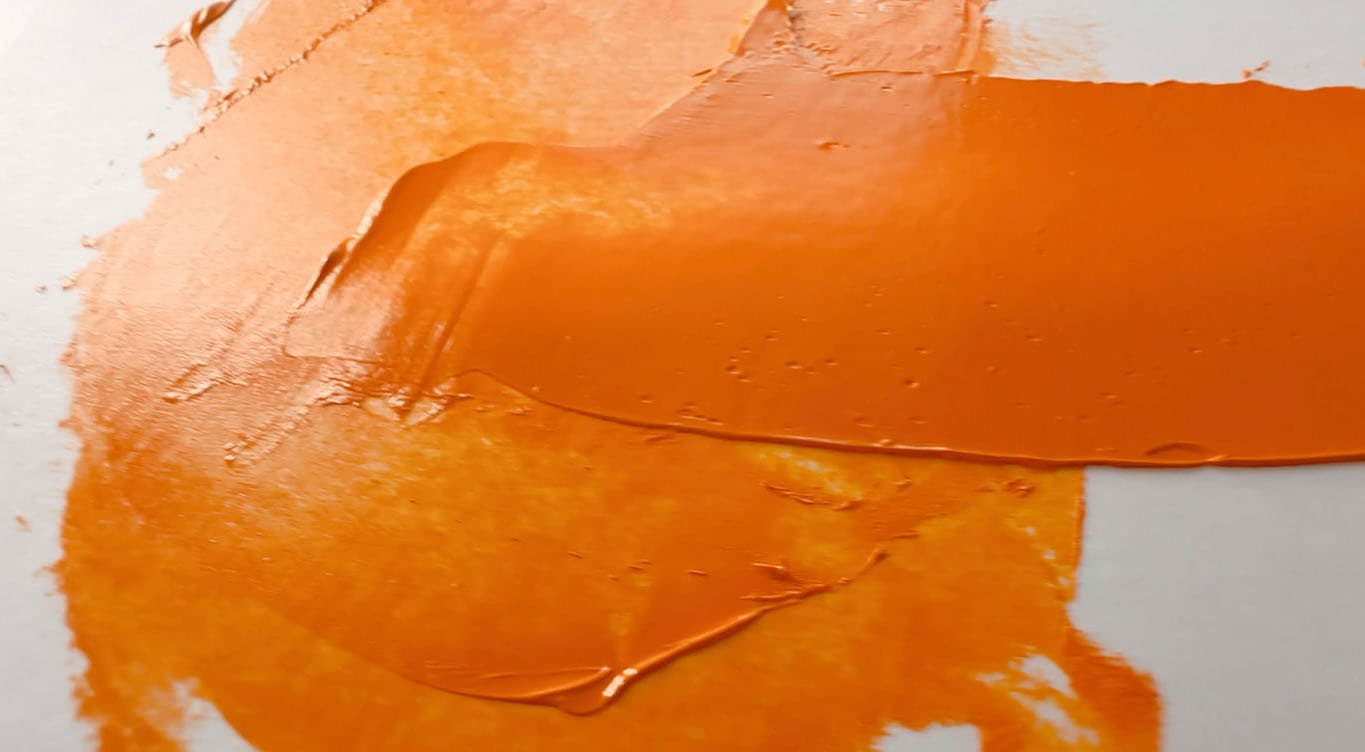 Orange oil paint made with PO62 pulled with a palette knife to illustrate semi-transparency