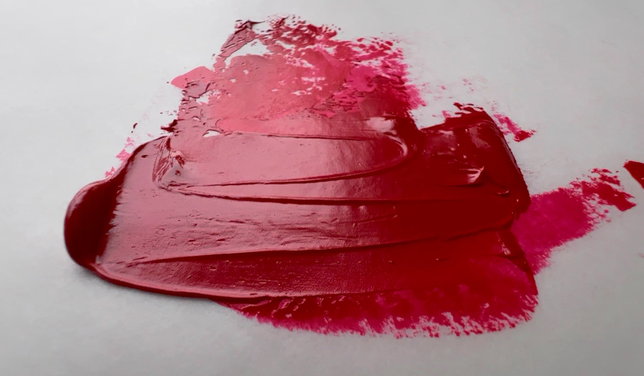 Magenta oil paint swooshed back and forth with a palette knife