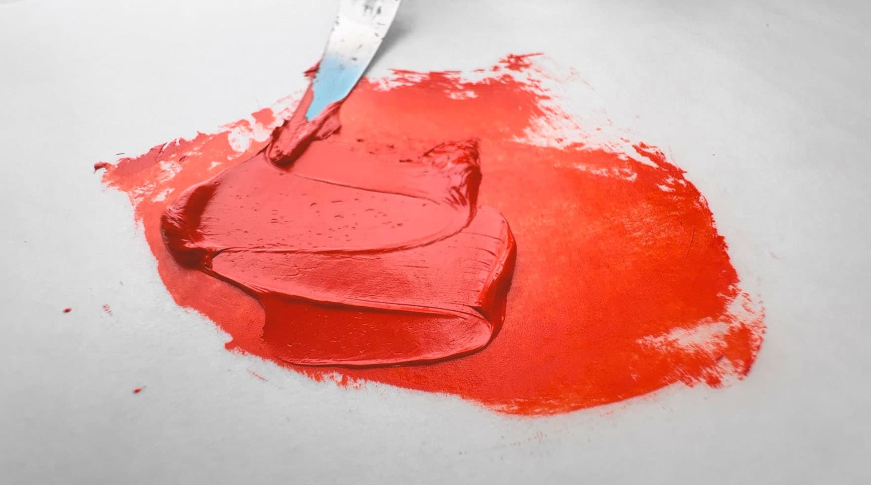 A swatch of bright red-orange oil paint