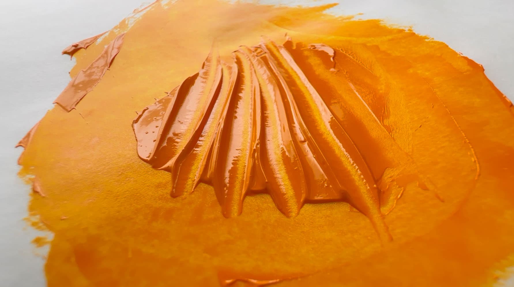 Impasto marks with a palette knife through a dollop of yellow-orange oil paint