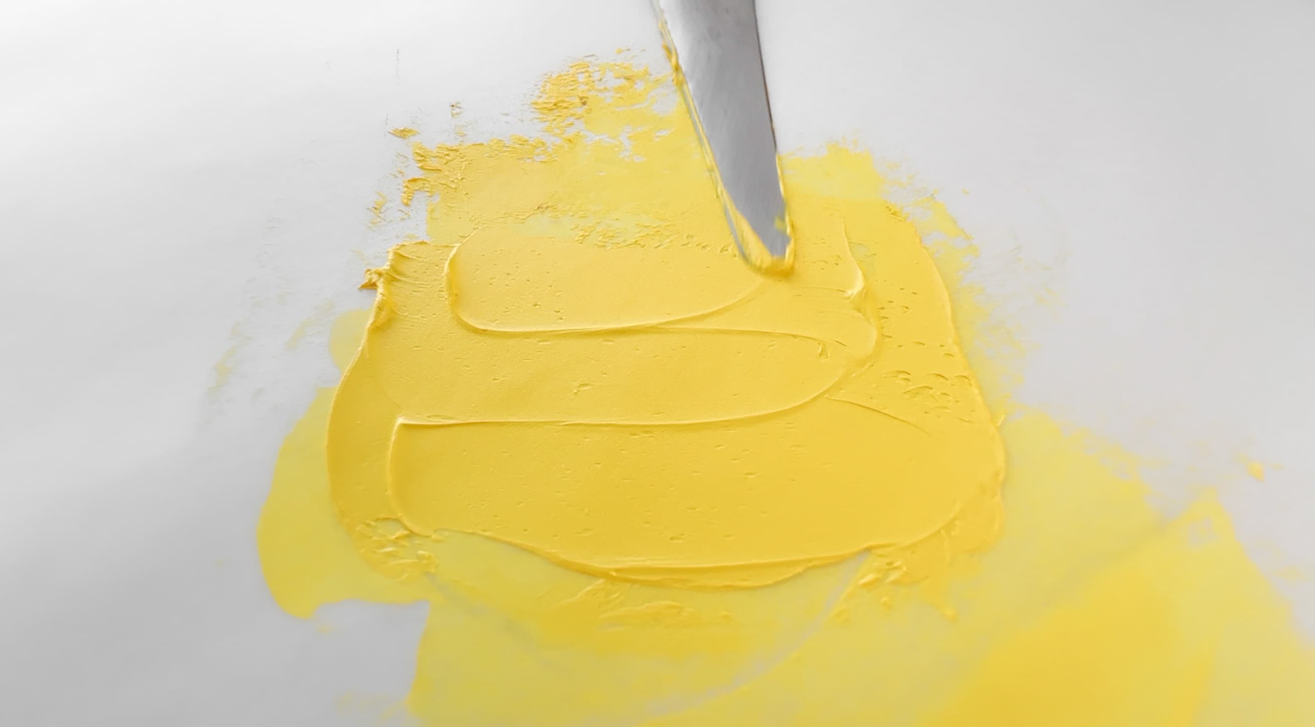 A bright yellow swatch of oil paint pulled by a palette knife